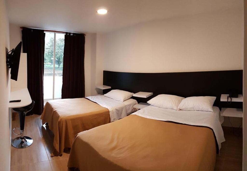 a hotel room with two beds and a piano at Hotel Villa Blanca in Popayan