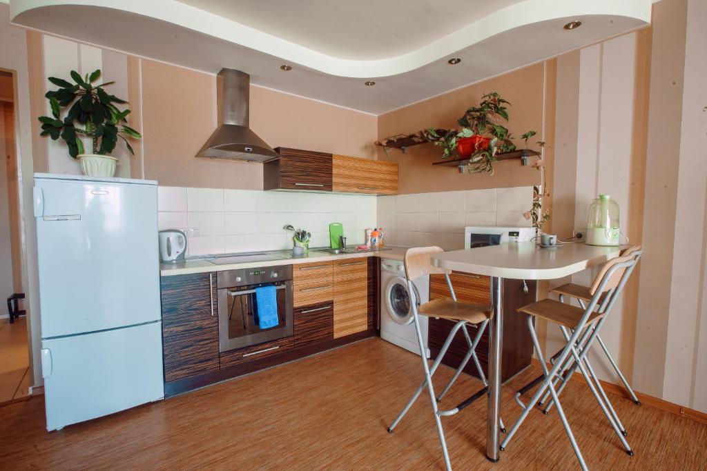 a kitchen with a white refrigerator and a table at Большая Подгорная 57 in Tomsk