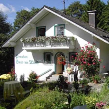 two people standing in front of a white house at Haus am Wald in Bayerisch Eisenstein