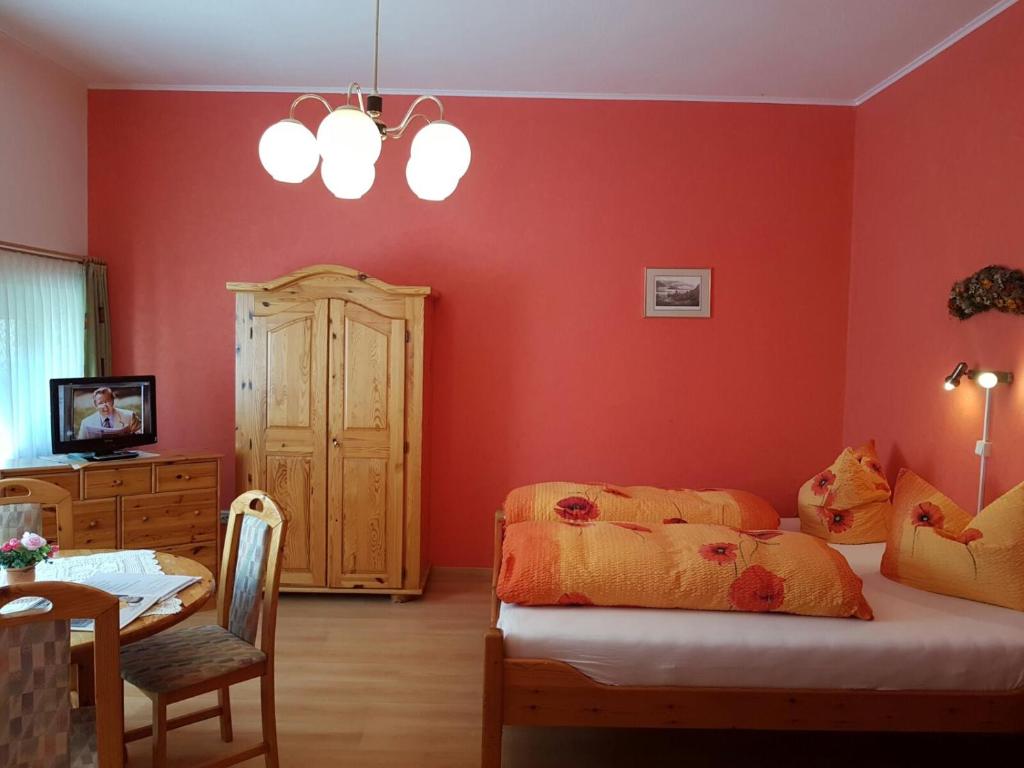 a bedroom with red walls and a bed and a table at Haus Andrea in Wernigerode