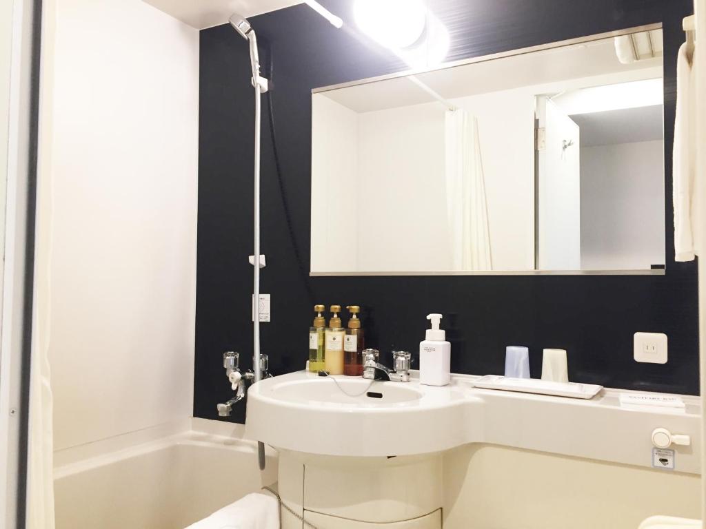a bathroom with a sink and a mirror and a tub at HOTEL MYSTAYS Kamata in Tokyo