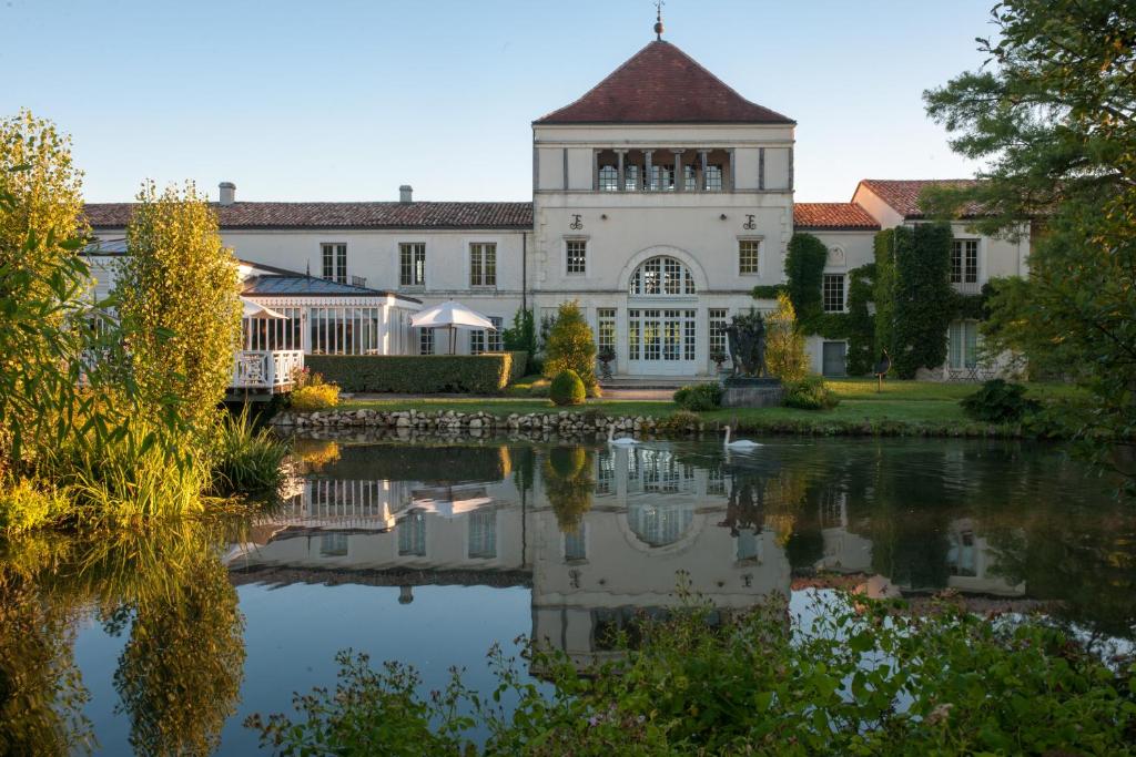 a large white building with a reflection in the water at Les Sources de Caudalie in Martillac