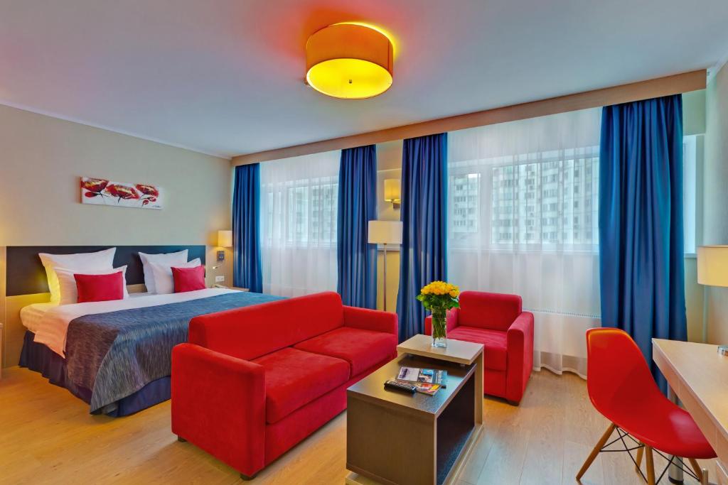 a hotel room with a bed and a red couch at Sevastopol Modern in Moscow