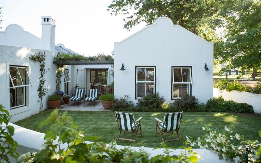 a white house with chairs in the yard at Vredenhof Farm Cottage in Elgin