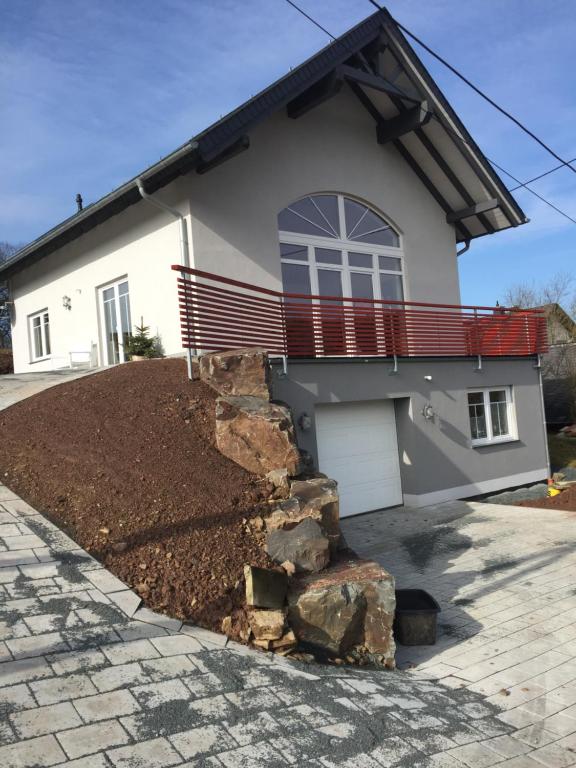 ein Haus mit einer Veranda und einer Auffahrt in der Unterkunft Artgerecht Ferienhäuser in Bad Berleburg