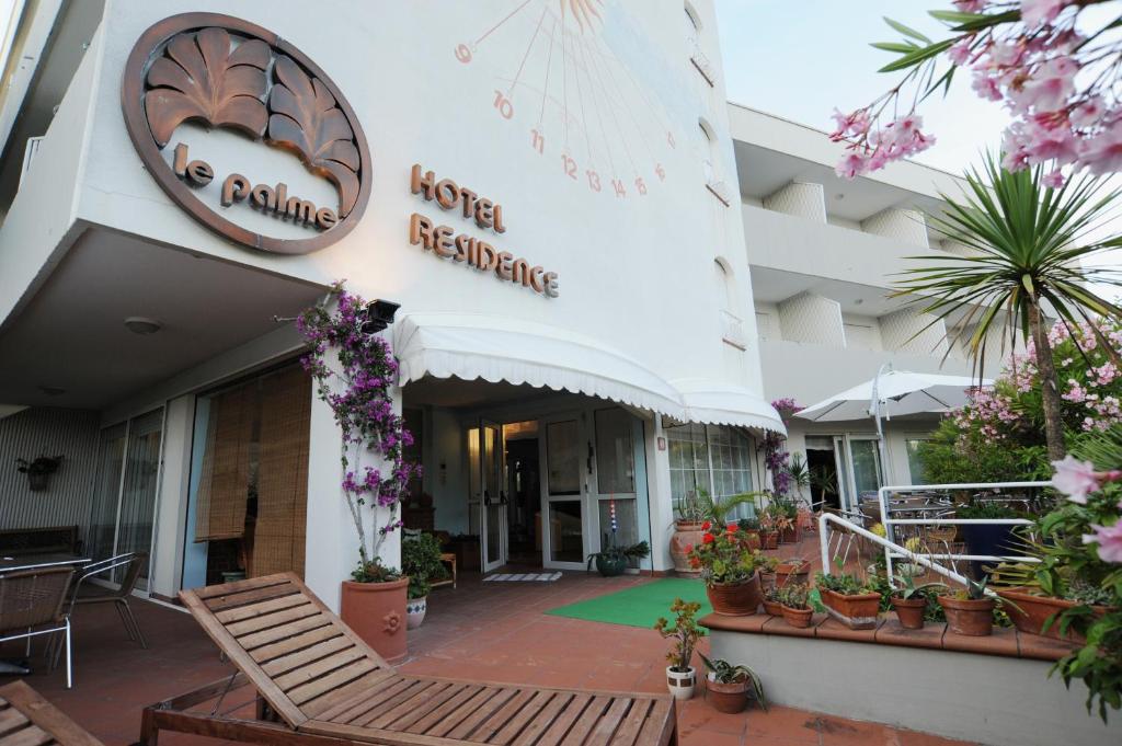 een hotelgebouw met stoelen en bloemen ervoor bij Hotel Le Palme " Adults only " in Grado