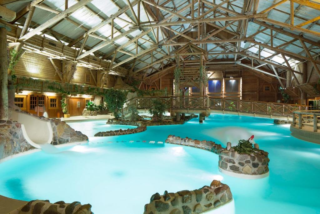 a large indoor swimming pool with blue water at Disney Davy Crockett Ranch in Villeneuve-le-Comte
