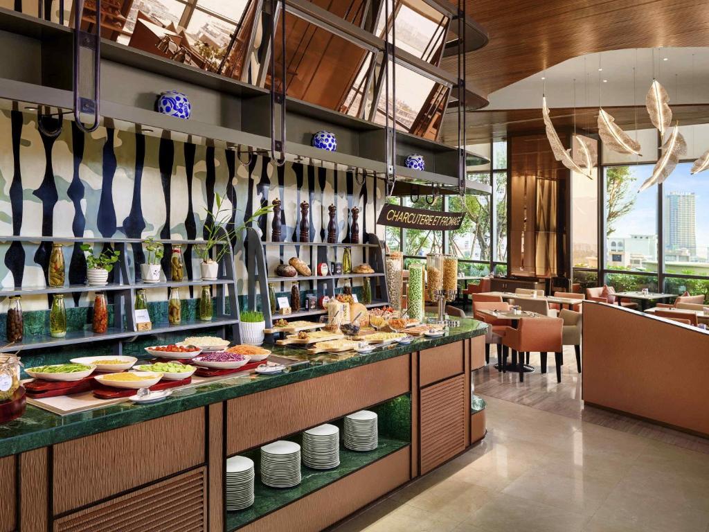 A stylish buffet line with prepared dishes, tableware, and a bright dining area beyond.