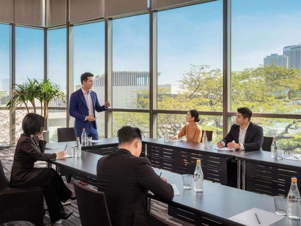 A window-lined meeting room is arranged for a presentation around a long table.