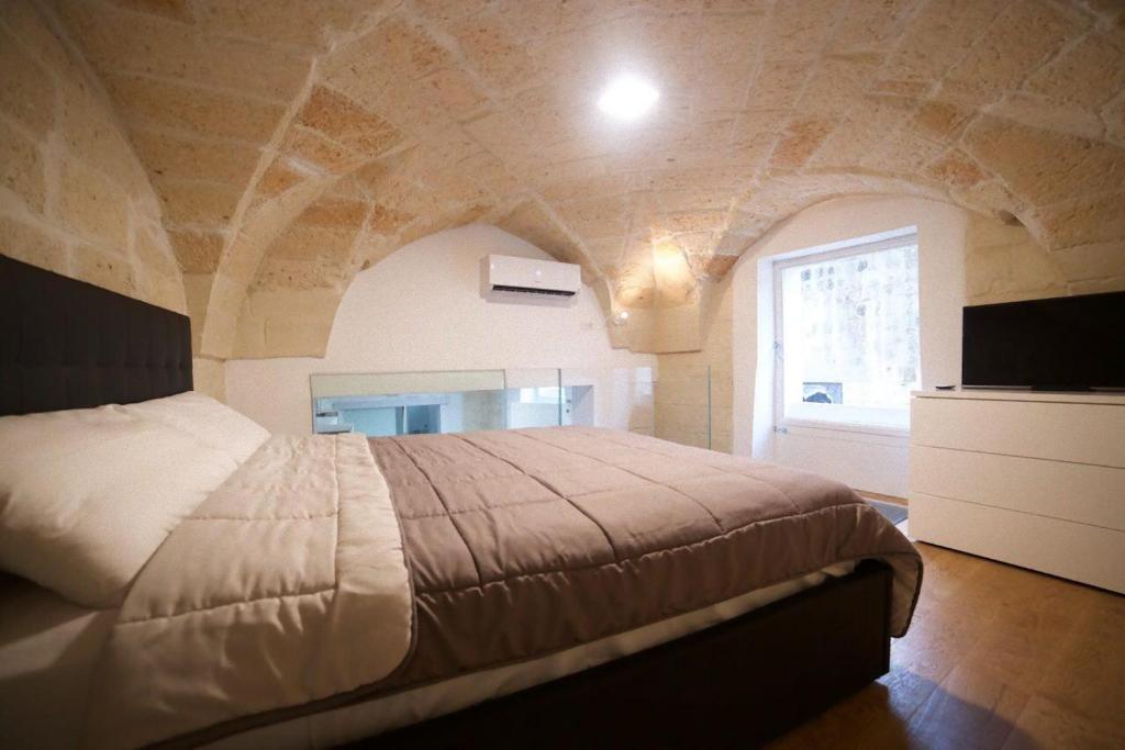 レッチェにあるSuite del Teatro Romanoの石壁のベッドルーム1室(大型ベッド1台付)