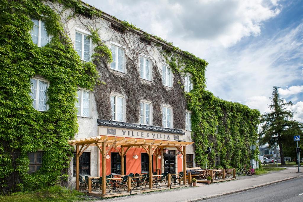 an ivy covered building with tables in front of it at Hotelli Ville in Tampere