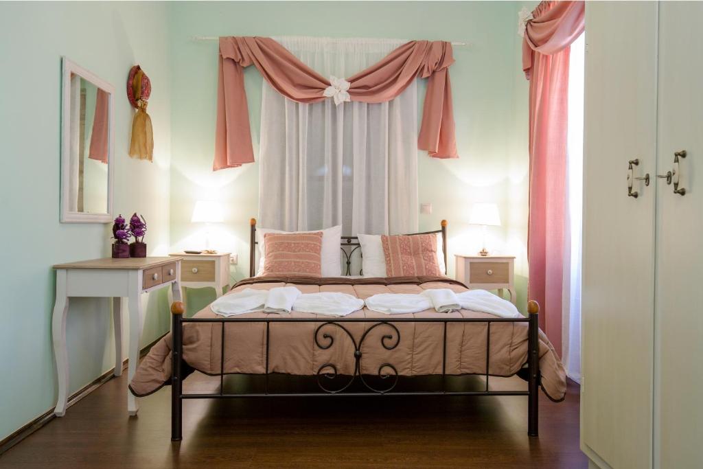 a bedroom with a bed and a window with pink curtains at Casa Di Porto in Chania