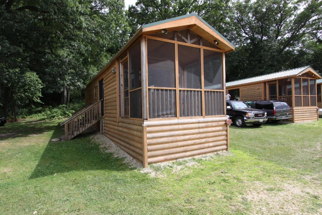 Cabaña de madera grande en un patio con coche en Blackhawk RV Campground Cabin 1, en Milton