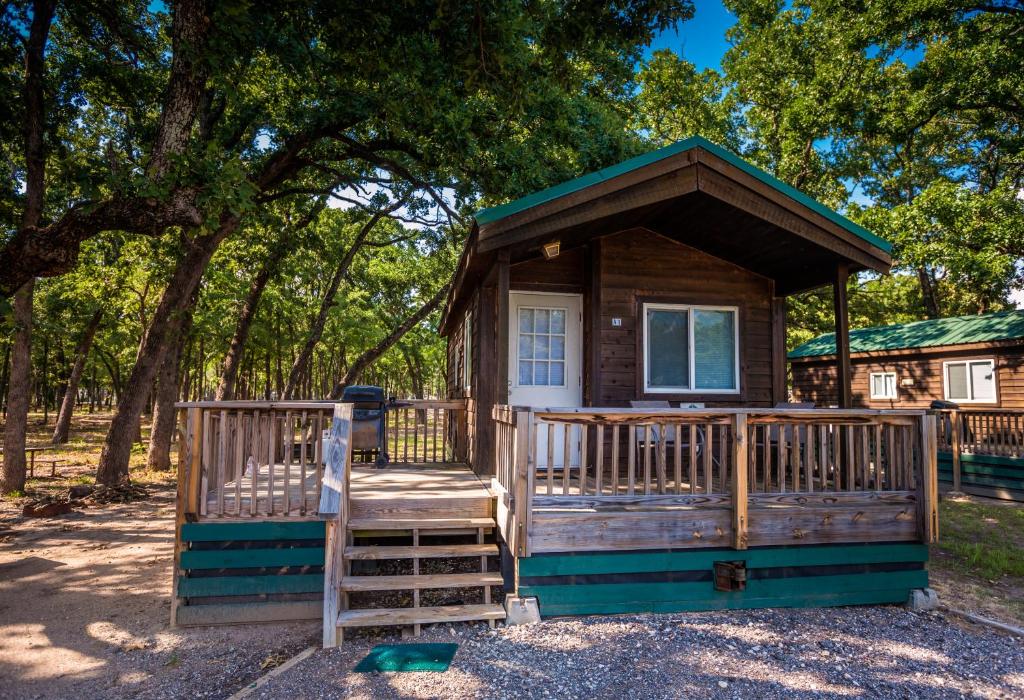 a cabin in the woods with a porch and trees at Pio Pico Camping Resort One-Bedroom Cabin 13 in Jamul