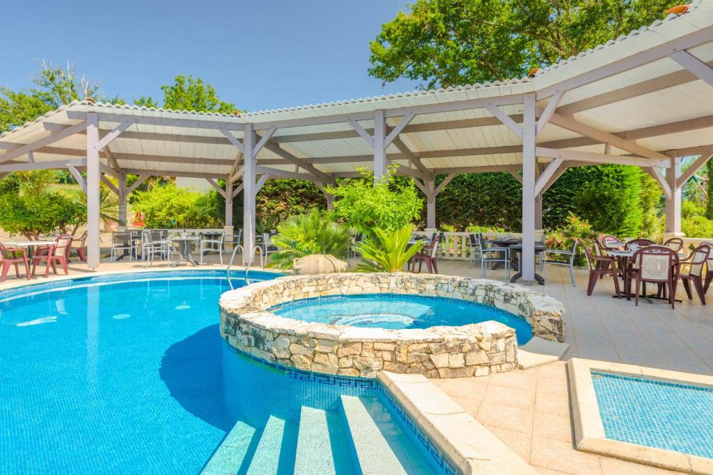 una piscina con pérgola y un patio con mesas y sillas en Hôtel Minvielle - Résidence Les Oliviers, en Ségos