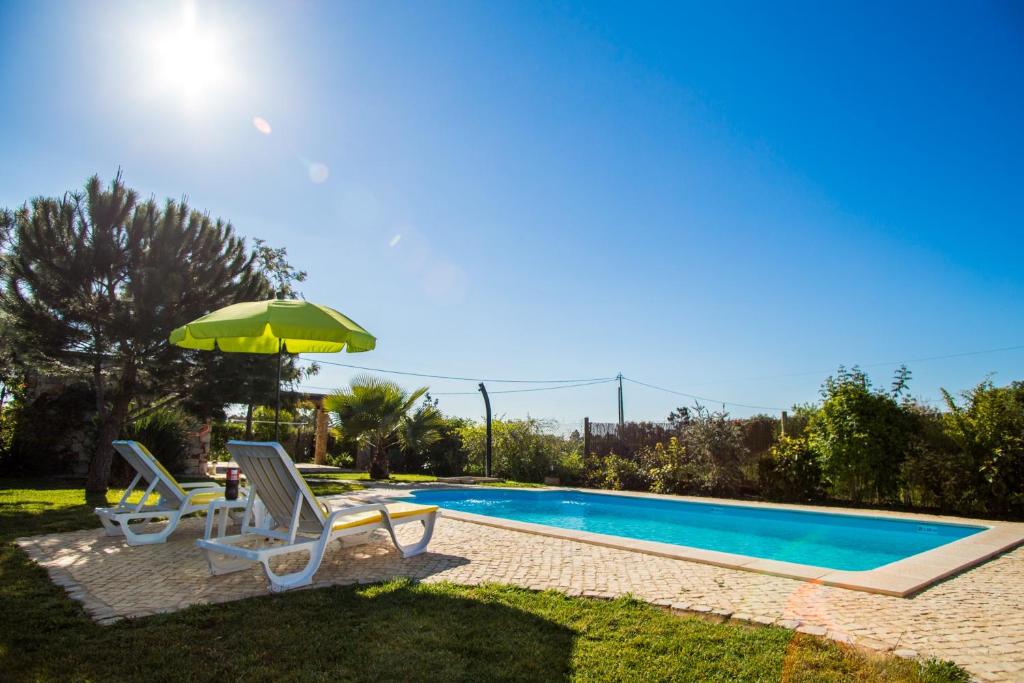 a swimming pool with two chairs and an umbrella at Akivillas Pera Relax in Pêra