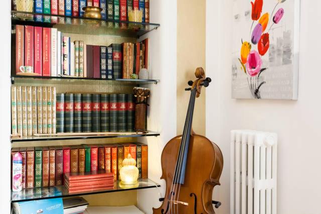 un violín sentado al lado de un estante de libros con libros en B&B Arts And Music en Ancona