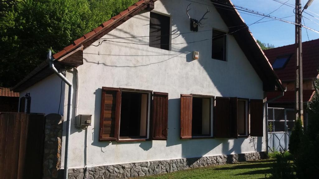 a white house with brown shuttered windows at Casa Sasca Montana in Sasca Montană