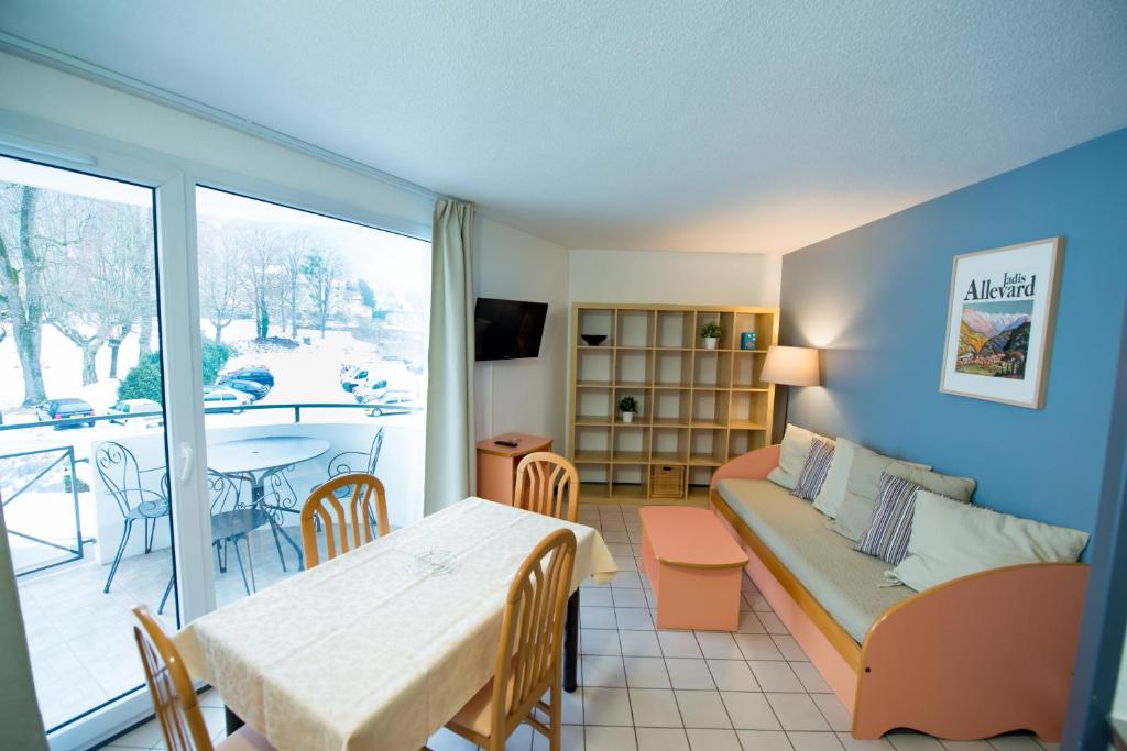 uma sala de estar com um sofá e uma mesa em Terres de France - Résidence les Silènes em Allevard