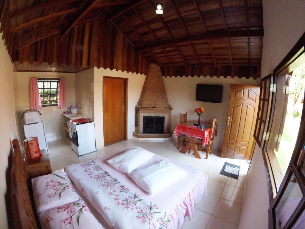 a bedroom with a bed and a kitchen with a fireplace at Monte Verde MG - Ana Júlia Chalés in Monte Verde