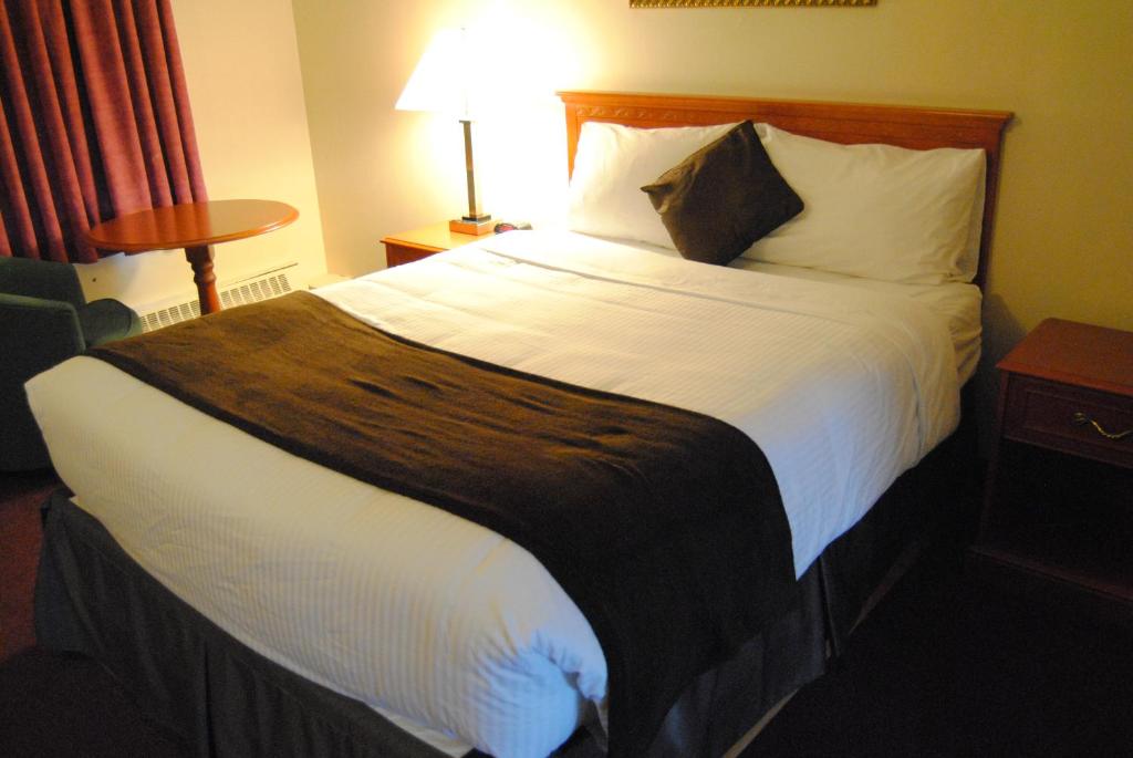 um quarto de hotel com uma cama grande com lençóis brancos em Economy Inn em Edmonton