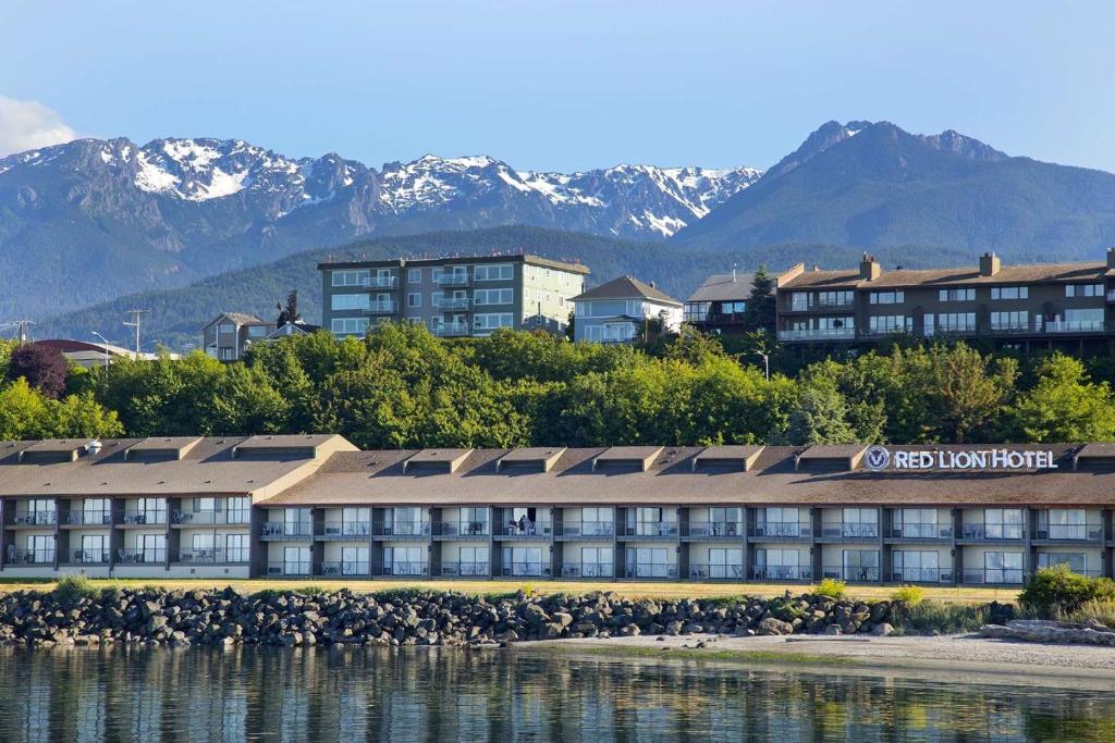 Red Lion Hotel Port Angeles Harbor في بورت انجيليس: فندق على المياه بجبال في الخلف