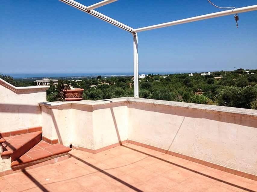 a balcony with a chair and a view of the ocean at La Mascherada in Ostuni