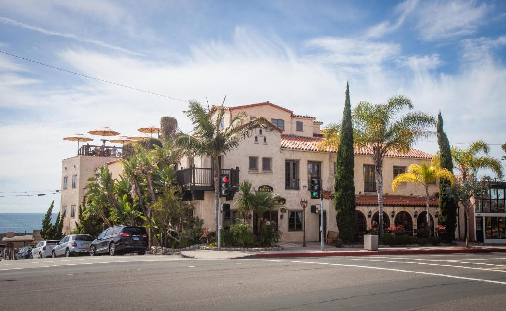 a building on the corner of a street with palm trees at La Casa Del Camino in Laguna Beach