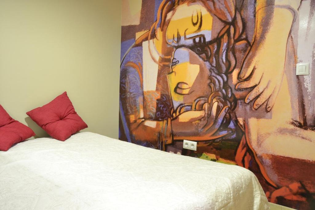 a bed with a painting on it and a painting on the wall at Hostal El Bugar in Teruel