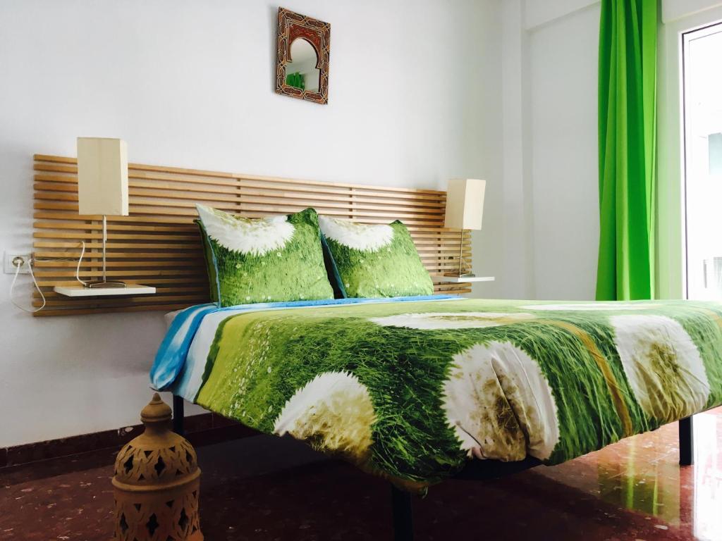 a bedroom with a large bed with green sheets and pillows at Axarquia Apartments in Nerja