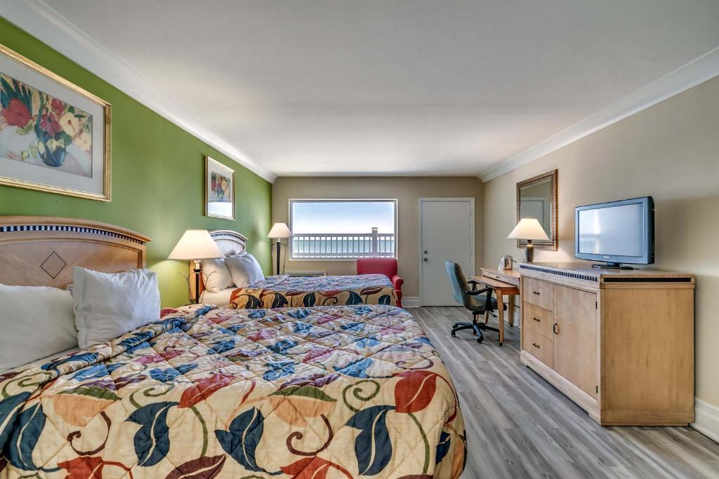 a hotel room with two beds and a flat screen tv at Beachcomber Inn & Suites in Myrtle Beach