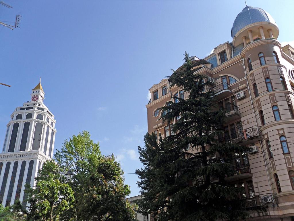 dois edifícios altos com uma árvore na frente deles em Batumi Elite Apartment em Batumi