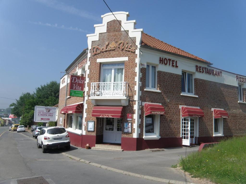 ein rotes Backsteinhotel mit einem davor geparkt in der Unterkunft Dolce Vita in Bruay-la-Buissiere