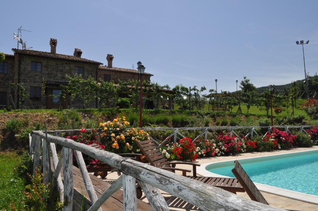 a pool with chairs and flowers next to a building at Agriturismo La Valle Dimenticata in Urbania