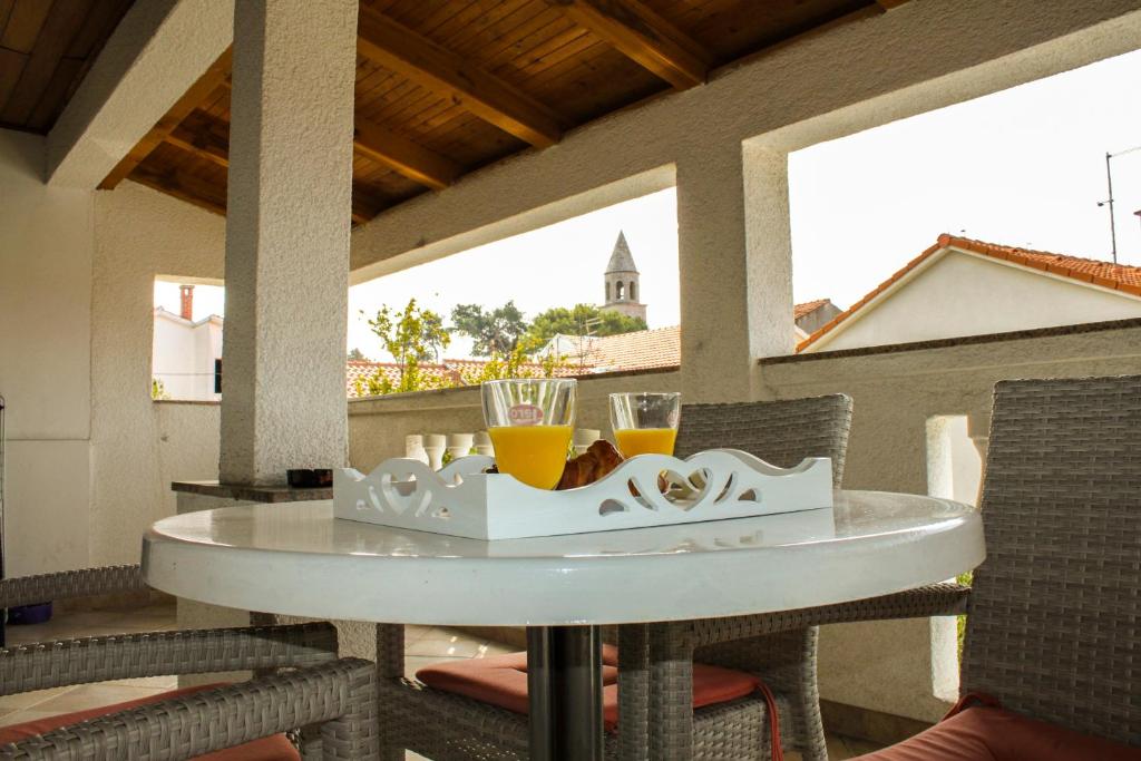 a table on a porch with two glasses of orange juice at Roko Apartments in Biograd na Moru