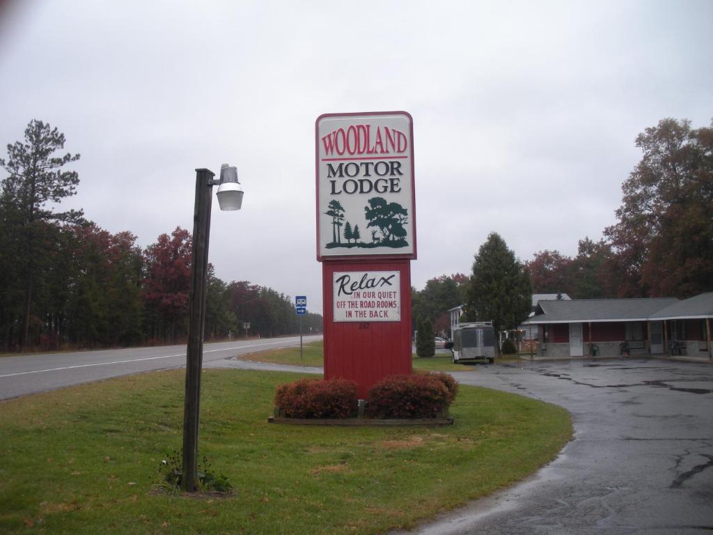 a sign for a motor lodge on the side of a road at Woodland Motor Lodge in Grayling