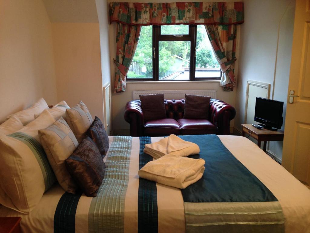 a bedroom with a bed with a couch and a window at Westgrange House Bed & Breakfast in Canterbury