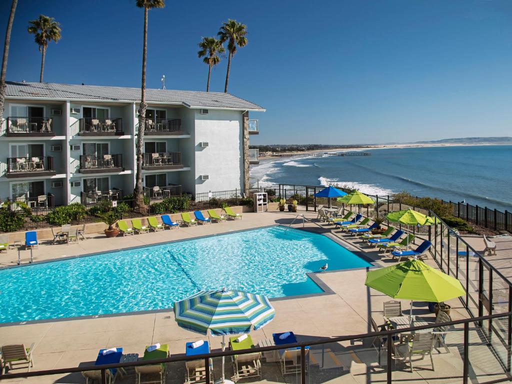 a beach area with a pool, chairs, and tables at Shore Cliff Hotel in Pismo Beach