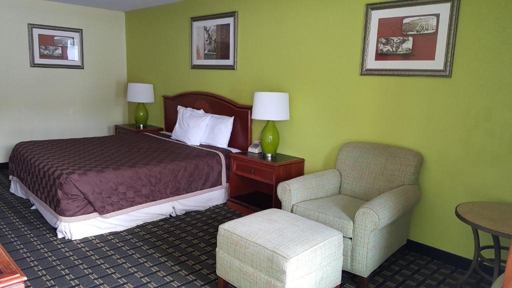 Habitación de hotel con cama y silla en American Inn Columbia, en Columbia