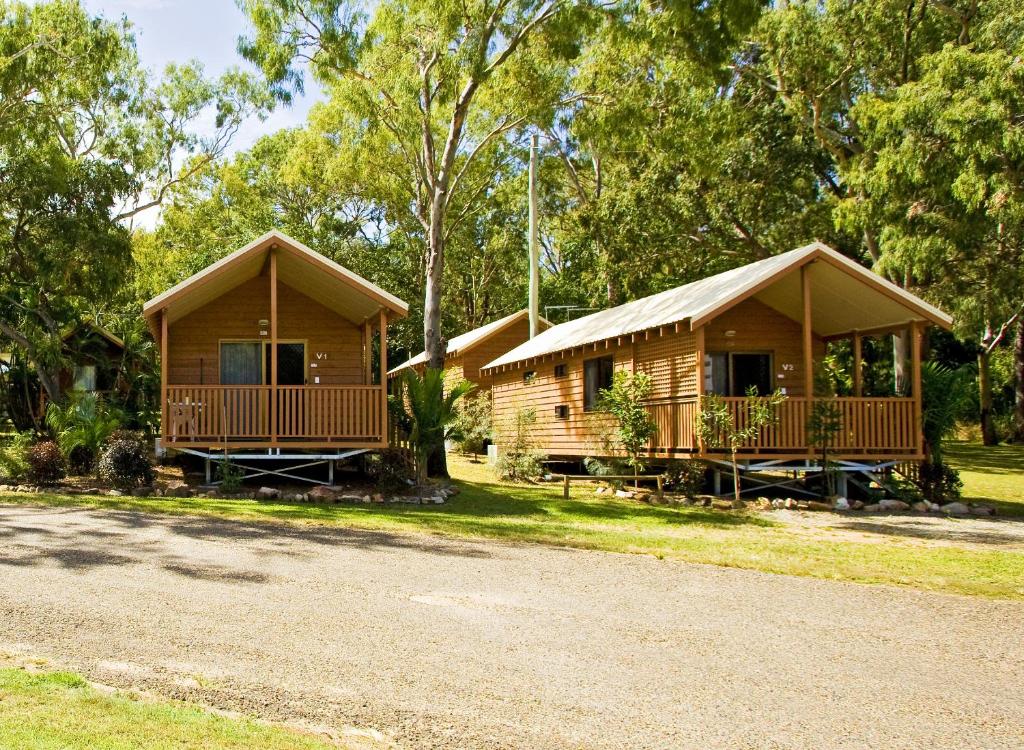 two wooden cottages with a gravel road in front at Captain Cook Holiday Village 1770 in Seventeen Seventy