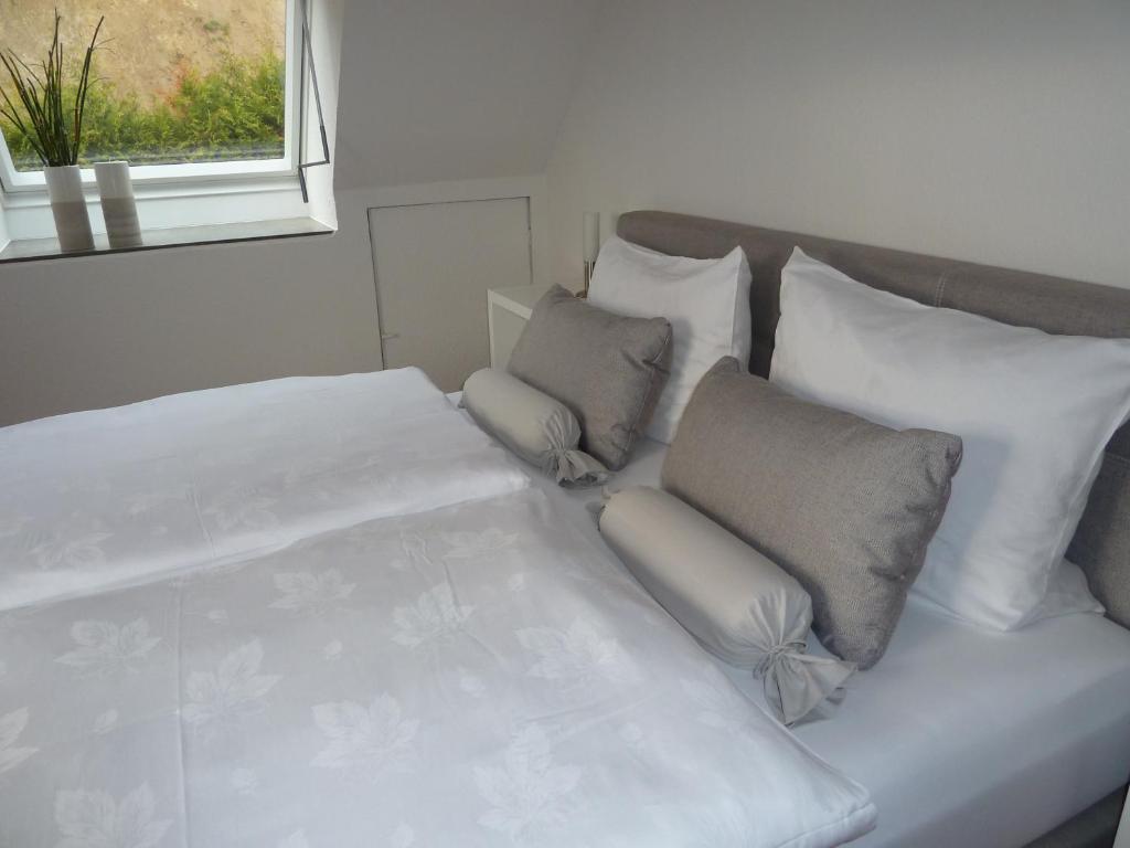 Cama blanca con almohadas blancas y ventana en Helle 70 qm Ferienwohnung mit herrlichem Blick, en Teningen