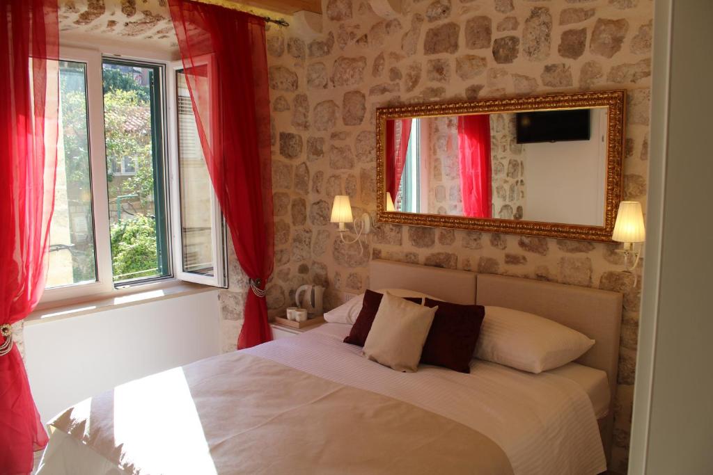 a bedroom with a bed with red curtains and a mirror at Villa Sigurata II in Dubrovnik