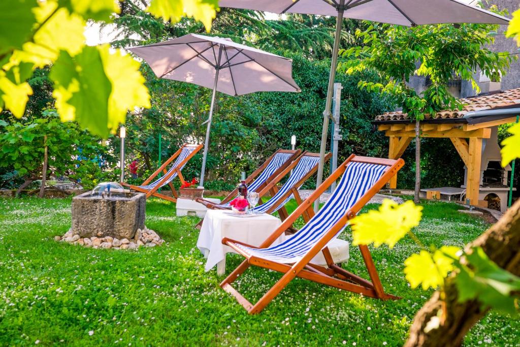 een groep ligstoelen en een parasol bij Apartments house Pinezic in Malinska