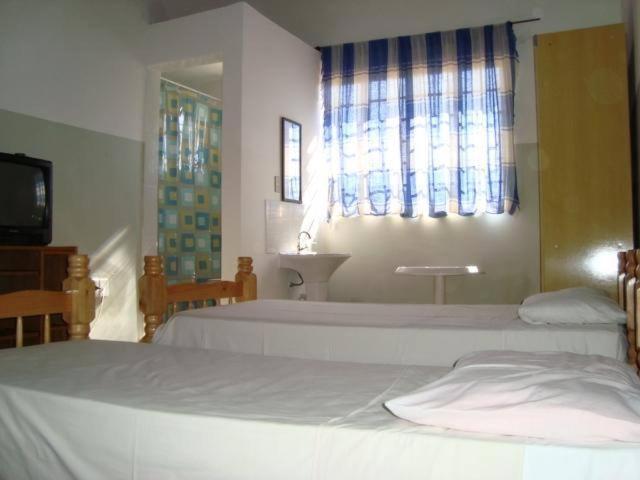 a bedroom with two beds and a sink and a window at Oriental Hotel in Sorocaba