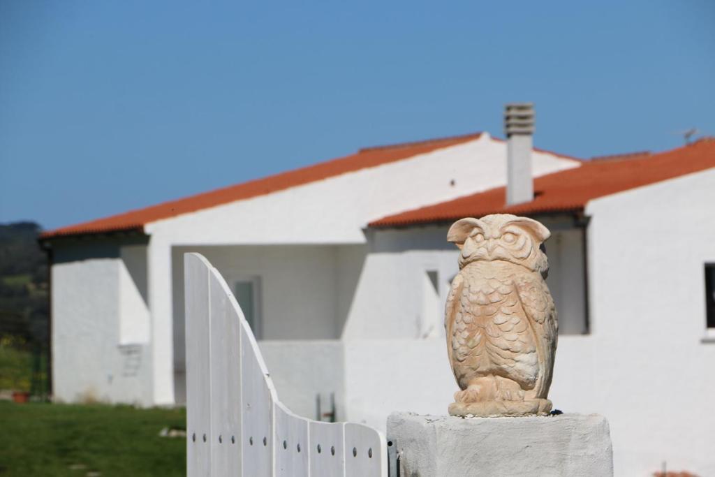 uma estátua de uma coruja sentada numa cerca em frente a uma casa em BnB Anacleto em Bassacutena
