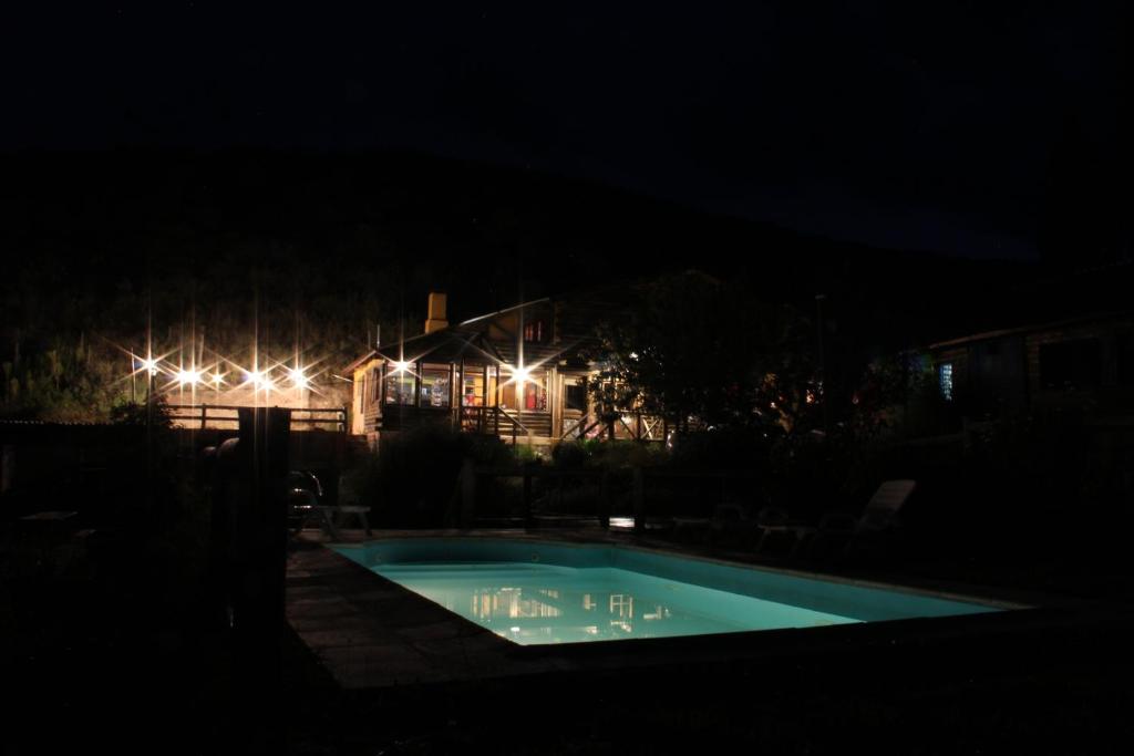 a swimming pool at night with a house in the background at Cabañas del Mesón in Potrerillos