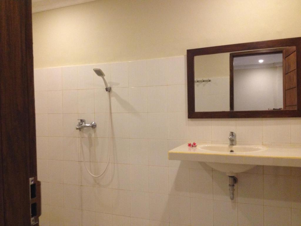 ein Badezimmer mit Dusche, Waschbecken und Spiegel in der Unterkunft Sinar Rinjani Cottage & Restaurant in Senaru