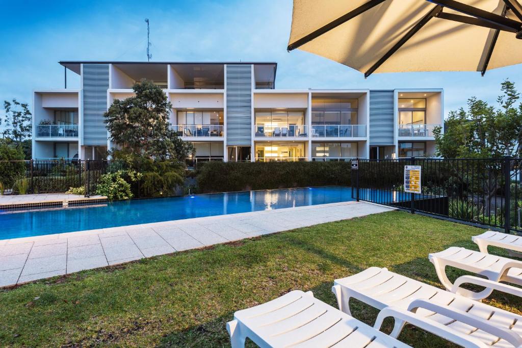 a large apartment building with a swimming pool and lounge chairs at Coast Resort Merimbula in Merimbula