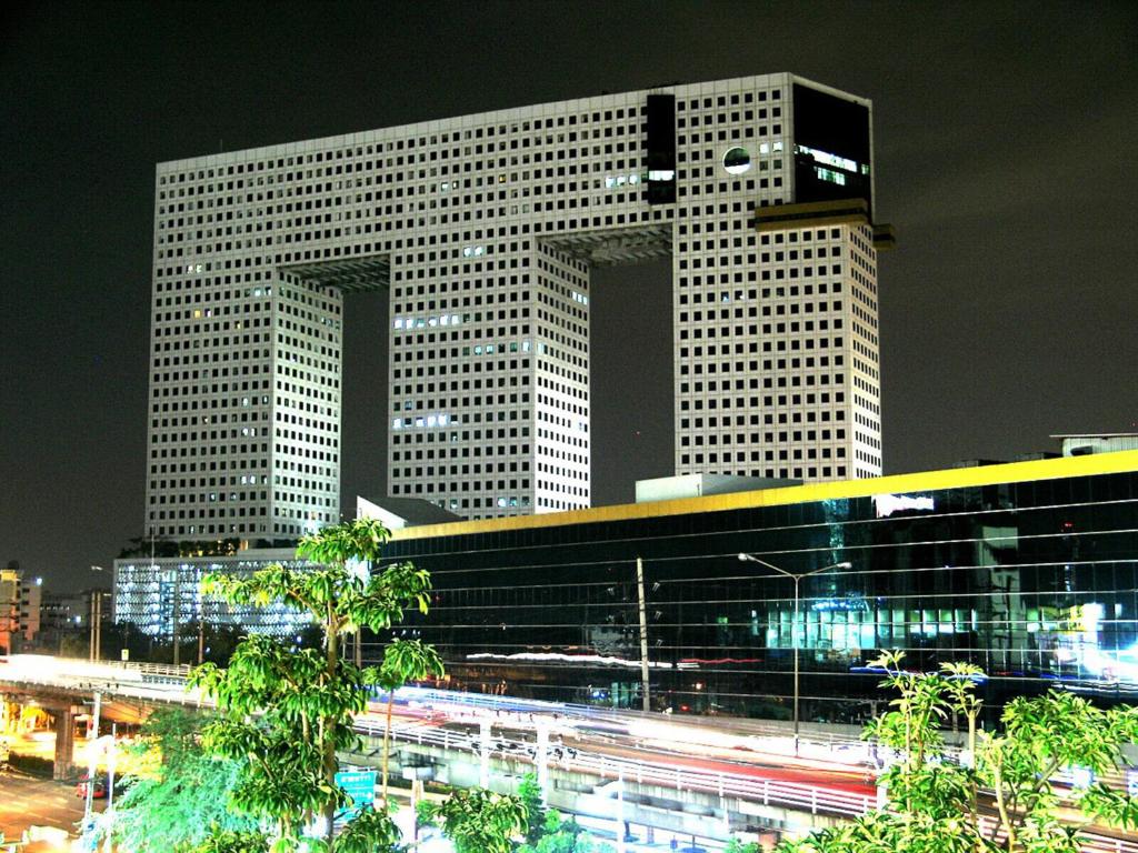 a tall building with a freeway in front of it at Iyarin @ Tuk Chang Hotel in Bangkok
