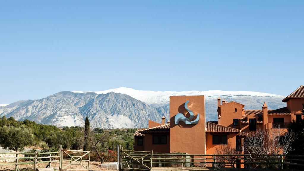 un bâtiment avec une fresque murale sur son côté avec des montagnes dans l'établissement Hotel & Winery Señorío de Nevada, à Villamena 
